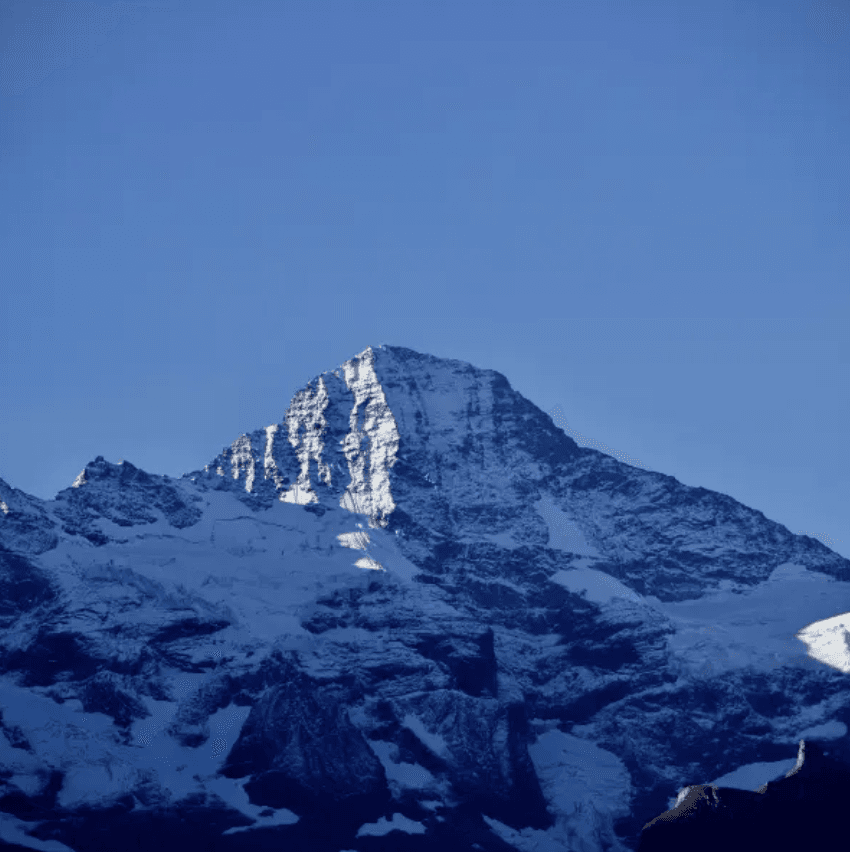 Snow-covered mountain peak against a clear blue sky.